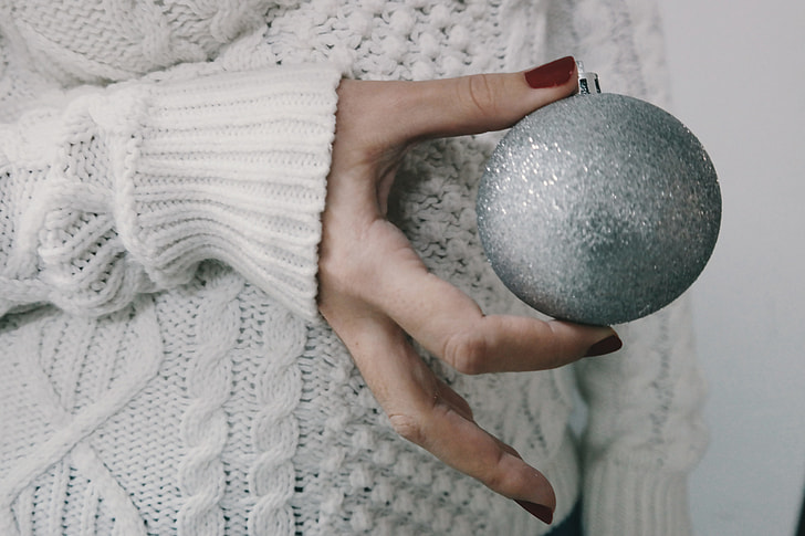 Person holding a silver Christmas decoration ball