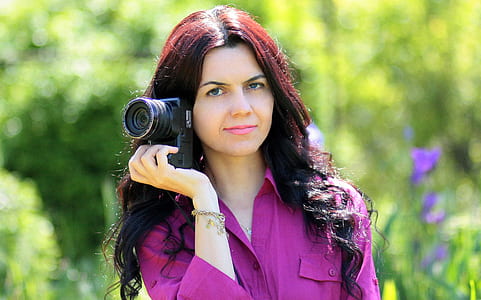 woman wearing purple dress shirt holding black DSLR camera