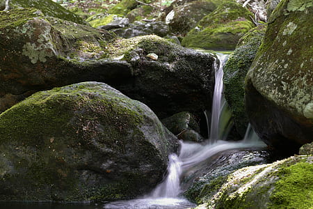 waterfalls on green rocky terrain during daytime