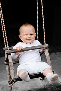 baby sitting on swing chair during daytime