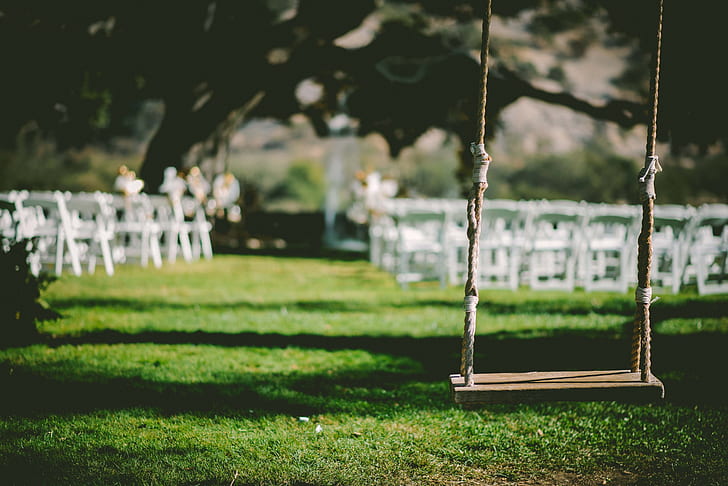 brown wooden base swing near white wooden chairs at daytime