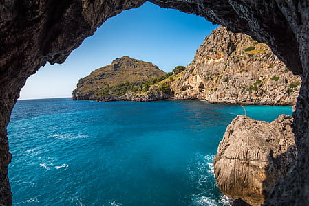 closeup photography of rock cave and blue sea