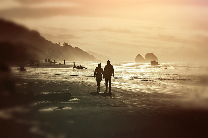 two person walking on beach during daytime