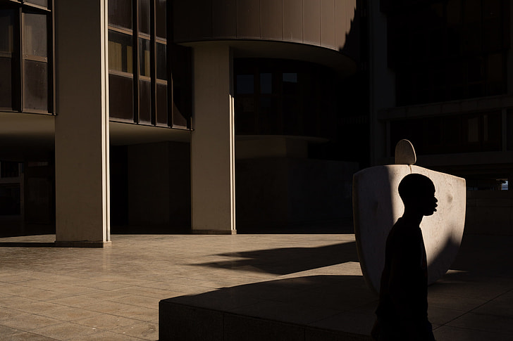 silhouette of man walking beside concrete building