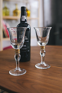 Two empty wine glasses with a bottle of wine on a table