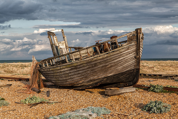 Wide-angle shot of an old abandoned fishing boat and nets. Image captured in Dungeness, Kent, England