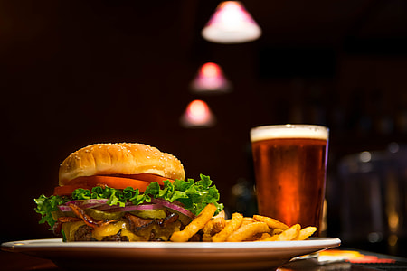 selective focus food photography of burger and fries on white ceramic plate with drinks