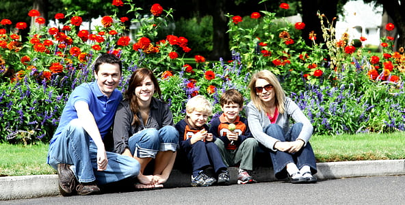 family sitting on road beside red poppy flowerss