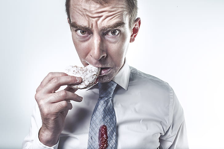 man wearing gray dress shirt eating a cookie