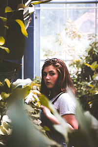 woman wearing gray shirt standing near green leaf plant during daytime