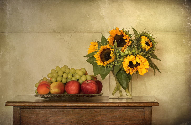 sunflower arrangement near bunch of fruits on brown wooden table