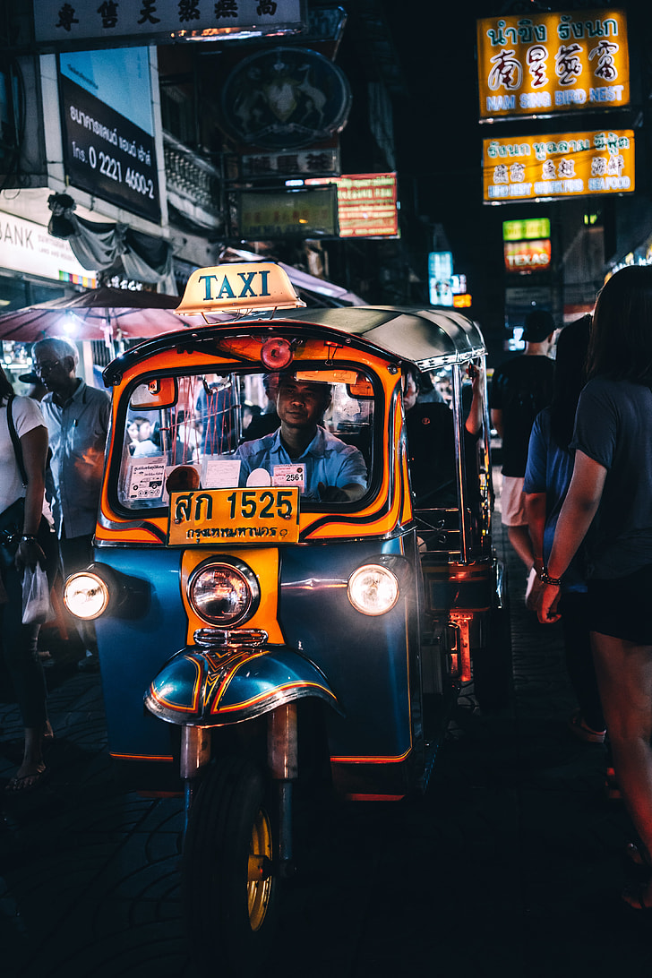 man riding blue and yellow auto rickshaw