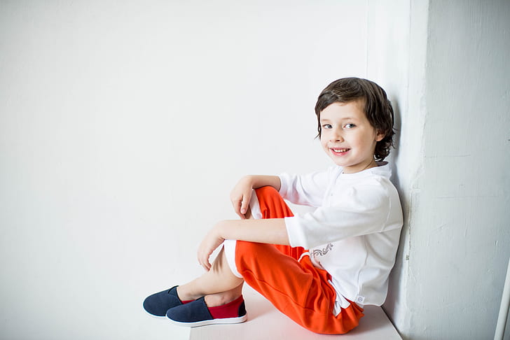 boy wearing white long-sleeved shirt and red pants