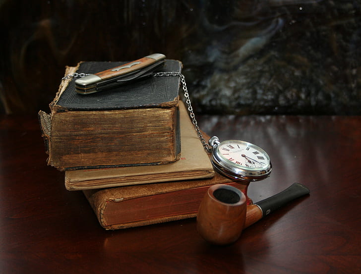 brown and black wooden pipe near books and pocket watch