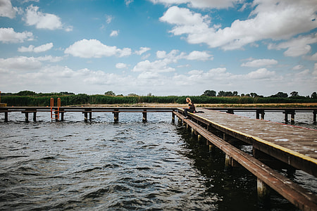 Beautiful blonde woman on a wooden pier by the lake