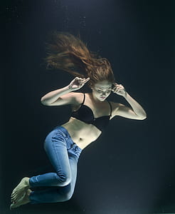 woman wearing black brassiere and jeans underwater