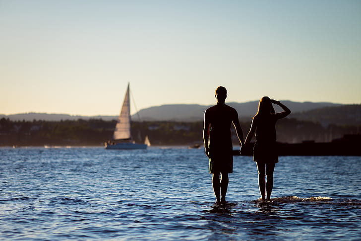 man and woman standing on body of water