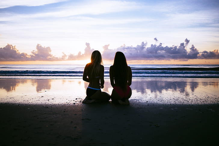 silhouette of two women sitting at seashore