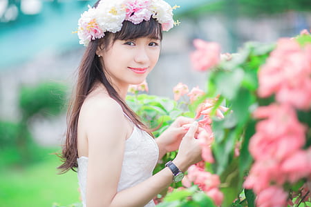 selective focus photography of woman in white top holding flowers
