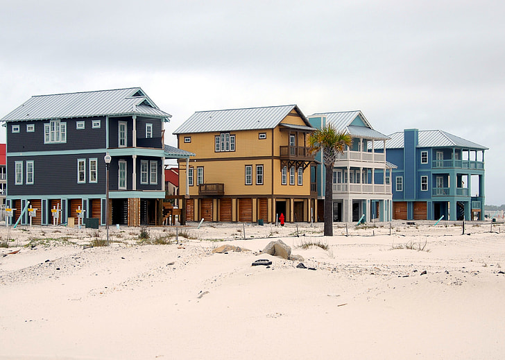 black, brown, and blue painted houses on brown sand under blue sky during daytime