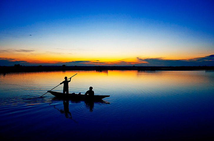 silhouette photography of two people on boat