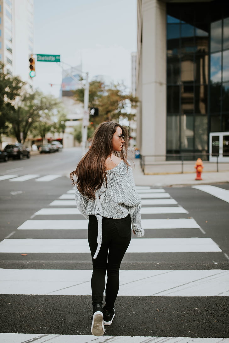 woman in gray sweater and black pants on pedestrian crossing during daytime