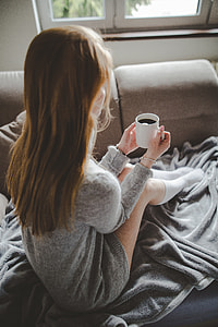 girl in grey knit sweater holding white ceramic mug