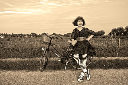 grayscale photography of woman in front of city bicycle