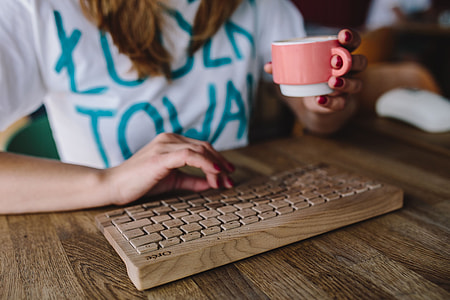 Closeup of female hands typing text on a wireless wooden keyboard