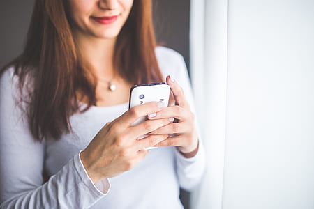woman holding white smartphone