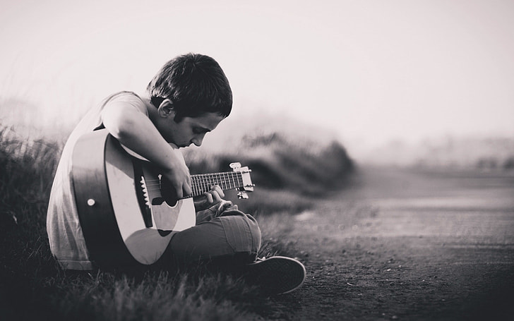 boy playing the guitar on the road