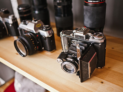 two black-and-gray assorted cameras on the brown wooden table