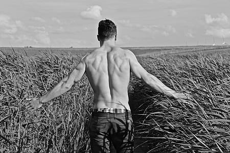 topless man in grass field grayscale