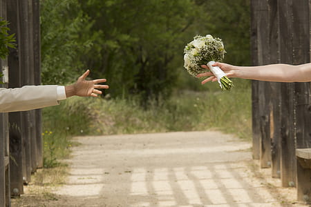 woman holding flower bouquet reaching man's hand