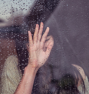 woman leaning on glass during rain