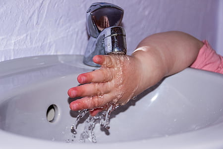 child washing right hand on white ceramic sink
