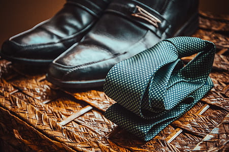 photo of folded green necktie beside pair of black leather dress shoes