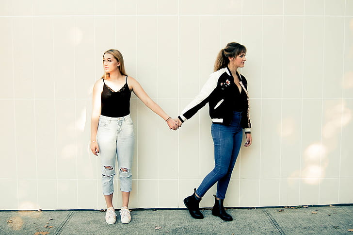 Two Women Standing Against Wall