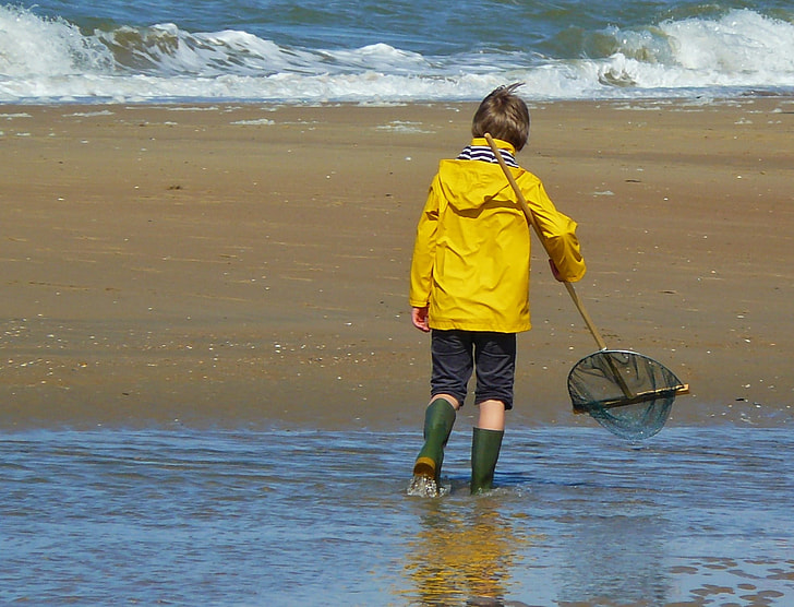 child walking on shore holding scoop net