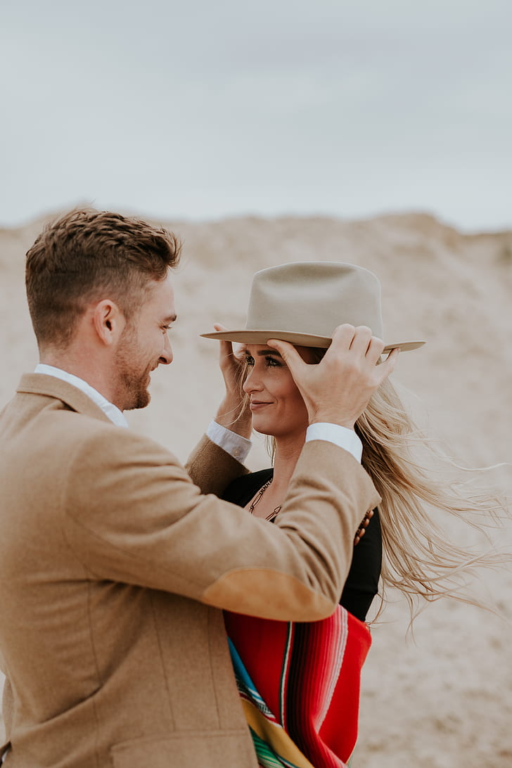 photo of man putting hat on woman