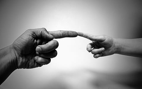 grayscale photography of two index fingers of two persons