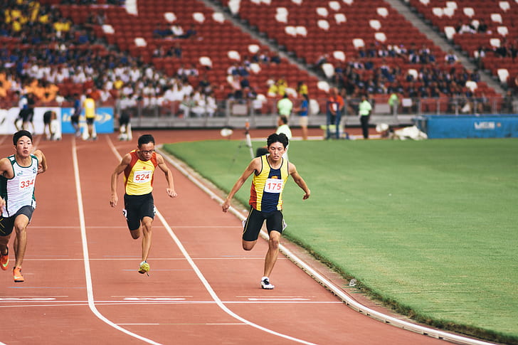 man in yellow tank top and black shorts running on track field