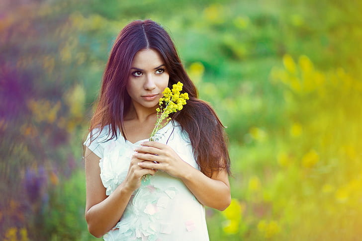 woman wearing black top holding yellow flowers