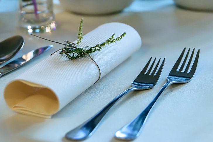 two gray stainless steel forks beside white table napkin