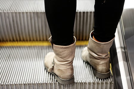 person wearing pair of beige leather boots on escalator