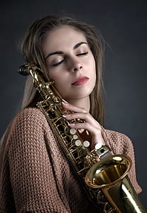 woman holding brass-colored saxophone