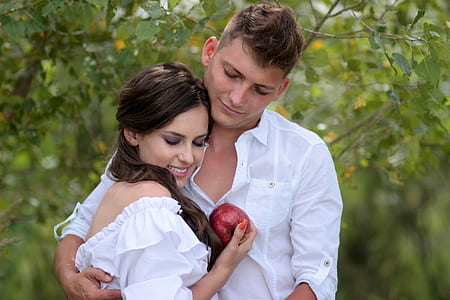 woman in white off-shoulder holding red apple man holding woman