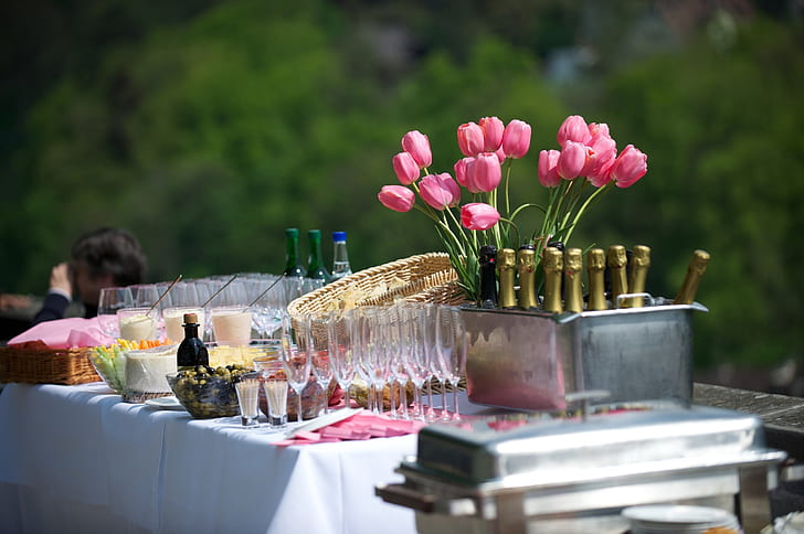 pink tulip flower arrangement beside wine glass and bottle on table