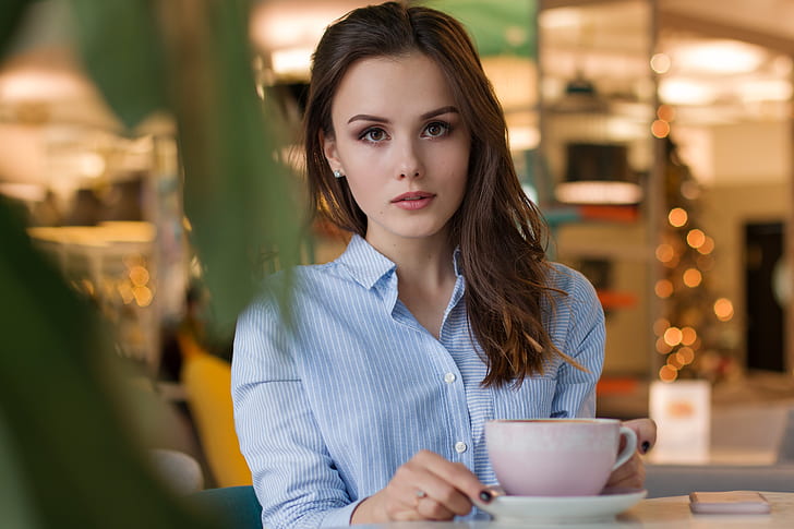 woman in blue shirt holding cup