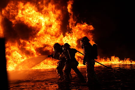 silhouette of three firefighters surrounded by fire